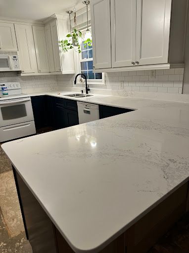 A kitchen with white cabinets and a white counter top.