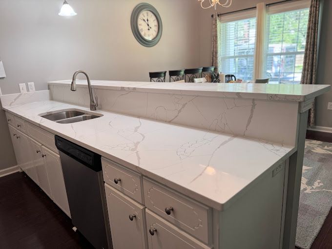 A kitchen with a sink , dishwasher , and a clock on the wall.