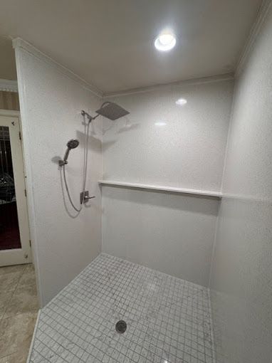 A shower with a shower head and a tiled floor in a bathroom.