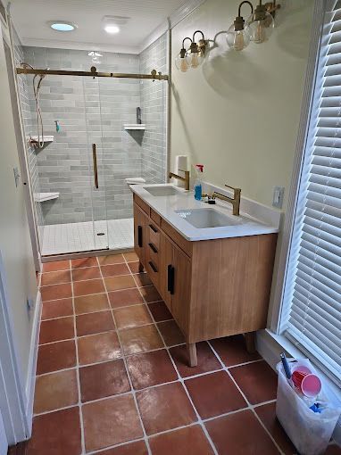 A bathroom with two sinks and a walk in shower.