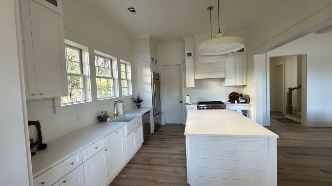 A kitchen with white cabinets and a large island.