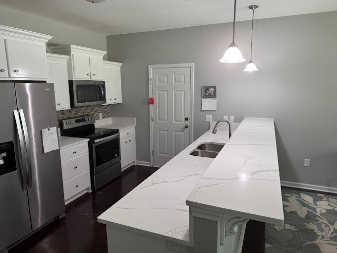 A kitchen with white cabinets and stainless steel appliances