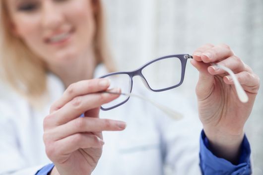 tecnico ottico porge occhiali da vista a cliente