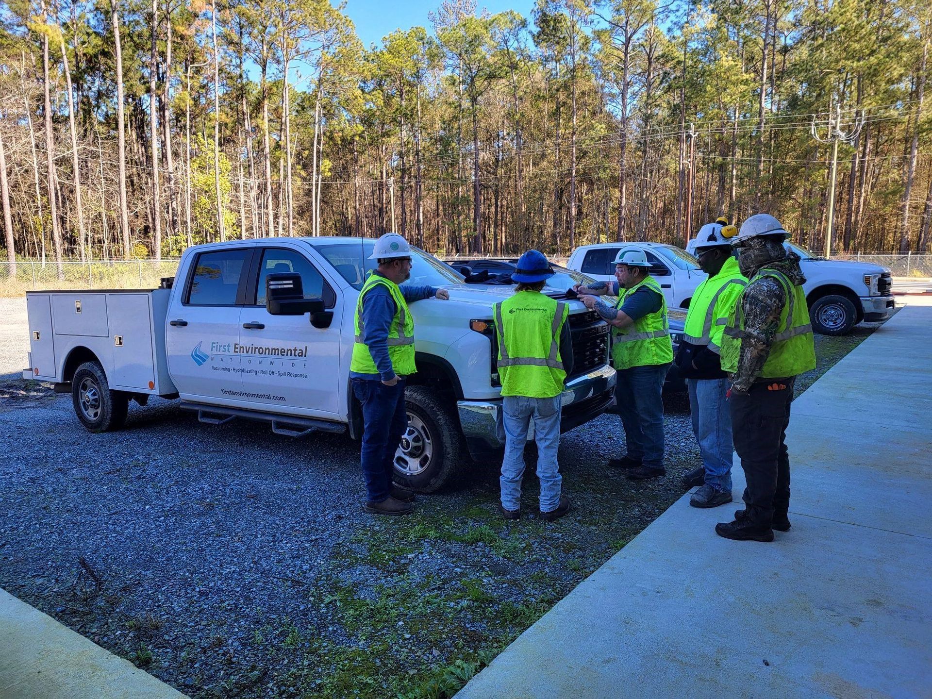 A group of First Environmental workers are meeting around a truck.