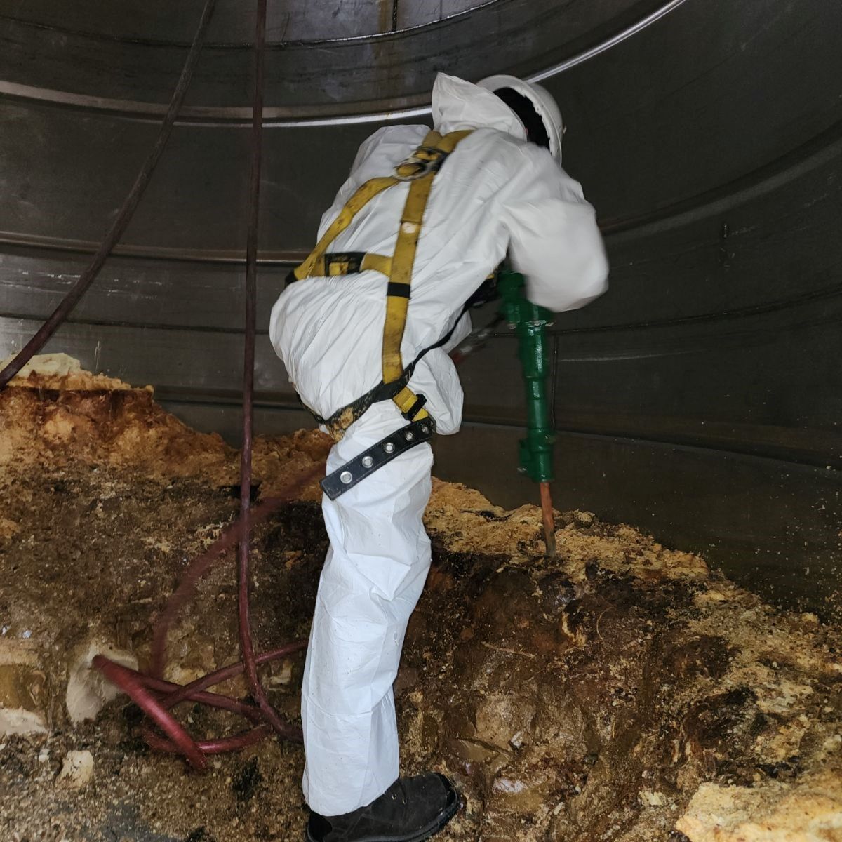 A man in a white suit is digging in the dirt