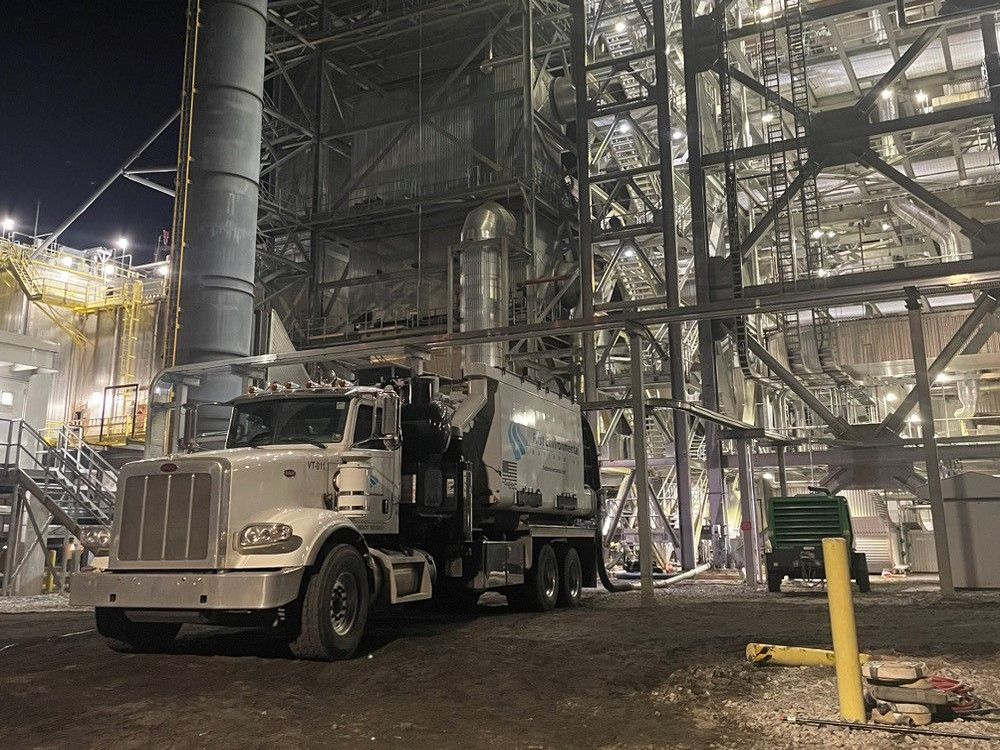 A First Environmental truck is parked in front of a large building at night