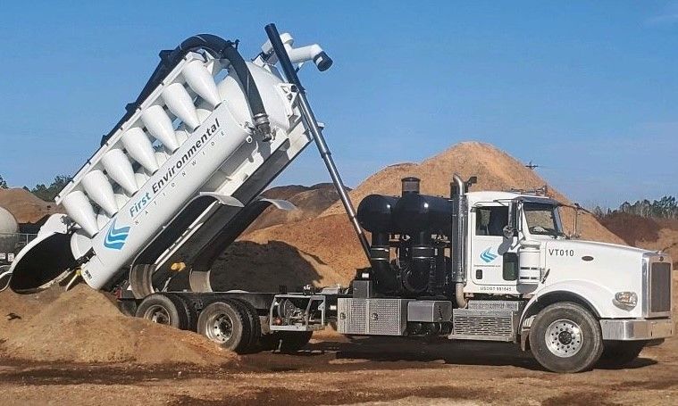 A vacuum truck is dumping dirt into a pile of dirt