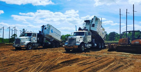 Two First Environmental vac trucks parked next to each other in a dirt field.