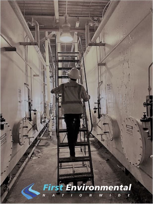 A First Environmental worker  is walking up a ladder in a factory.