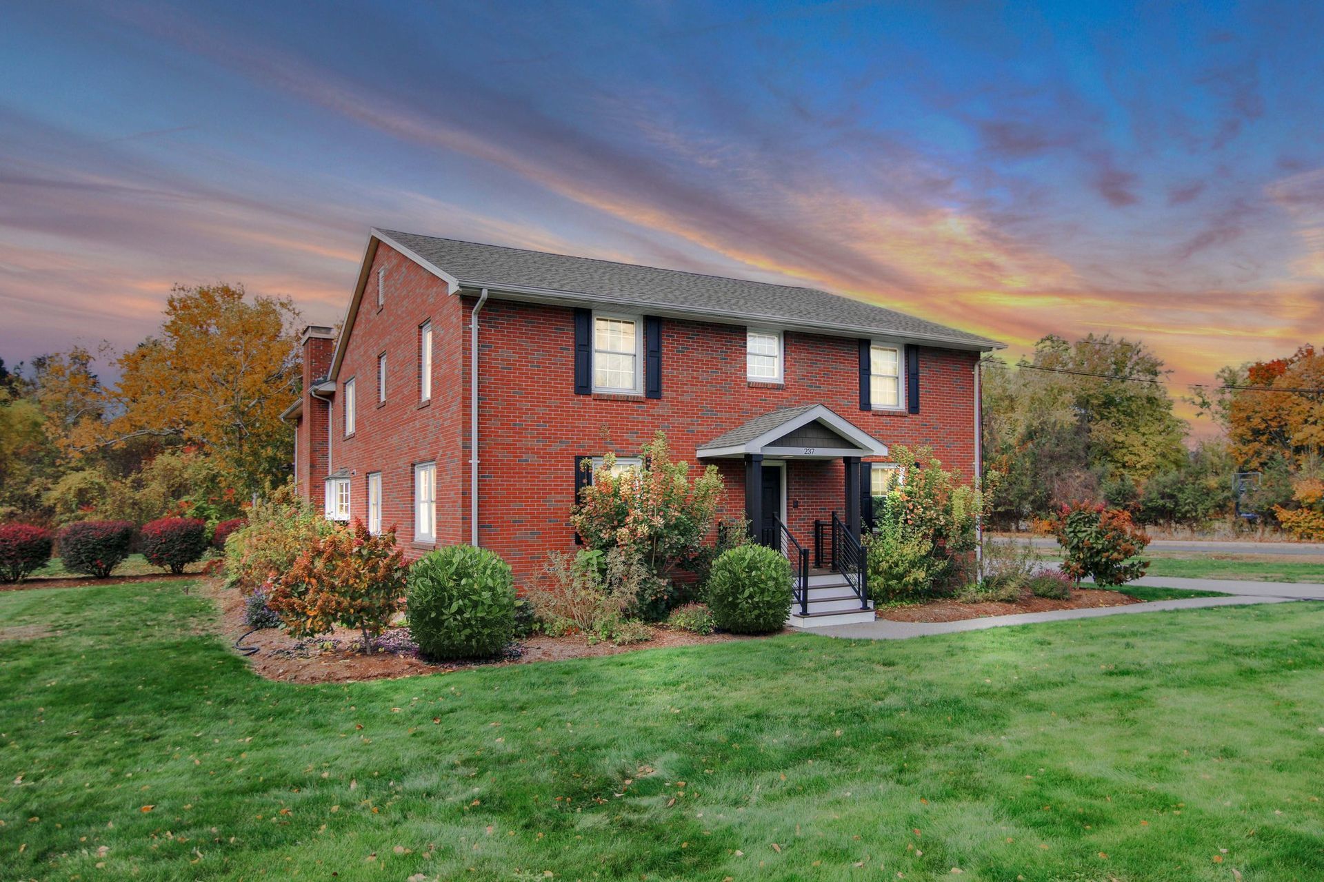 A large red brick house with a large lawn in front of it.