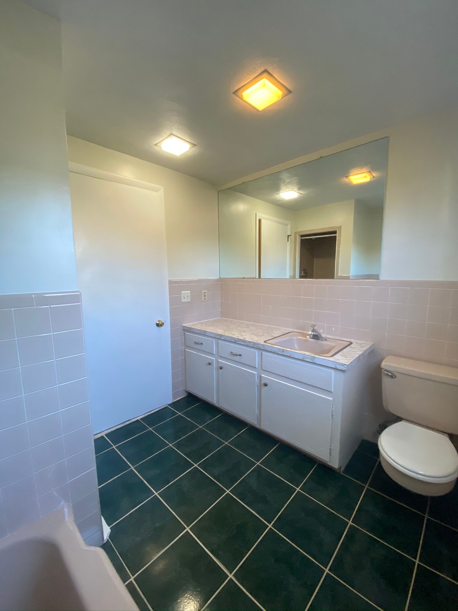 A bathroom with a toilet , sink , and mirror.