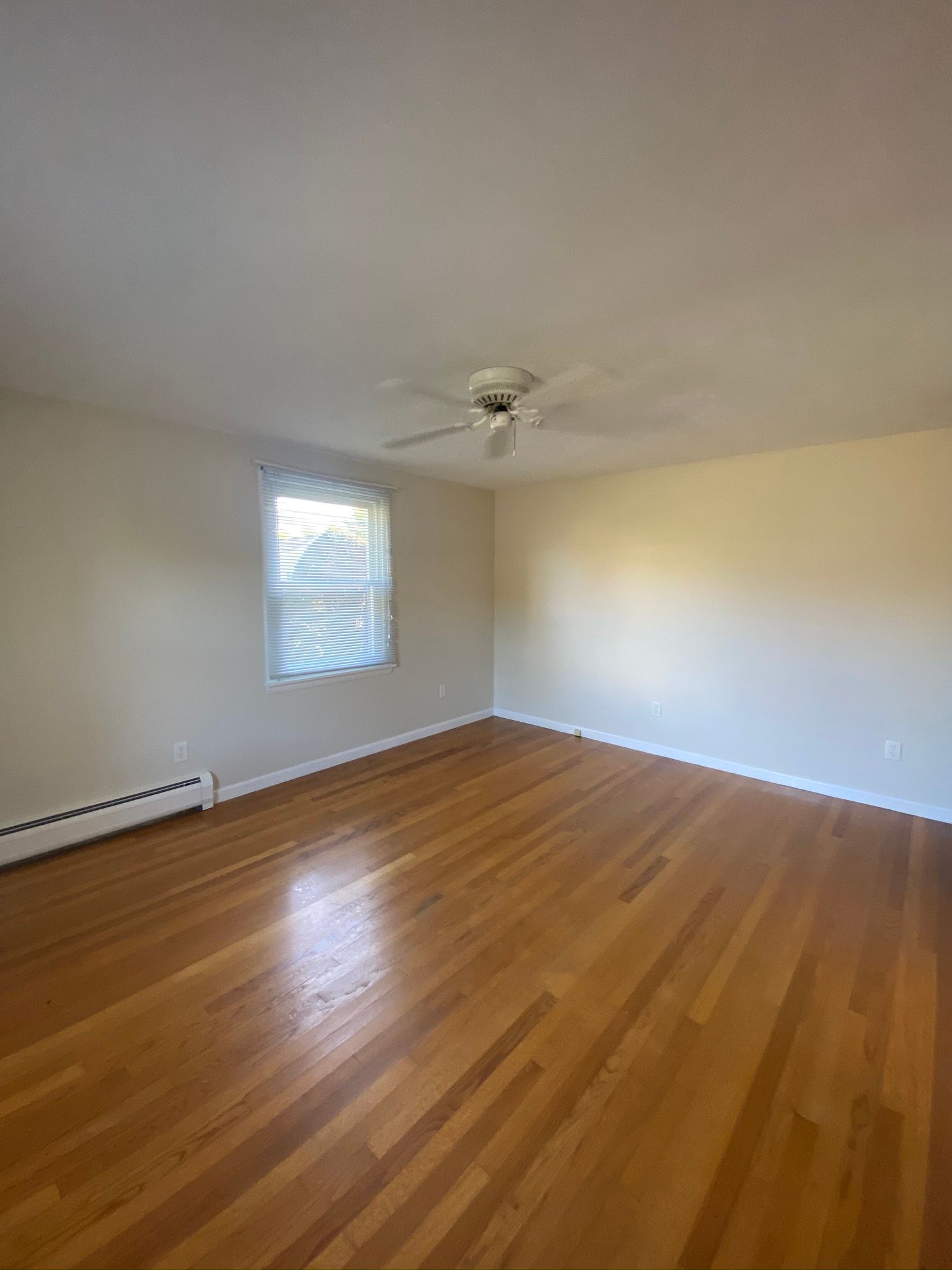 An empty living room with hardwood floors and a ceiling fan.