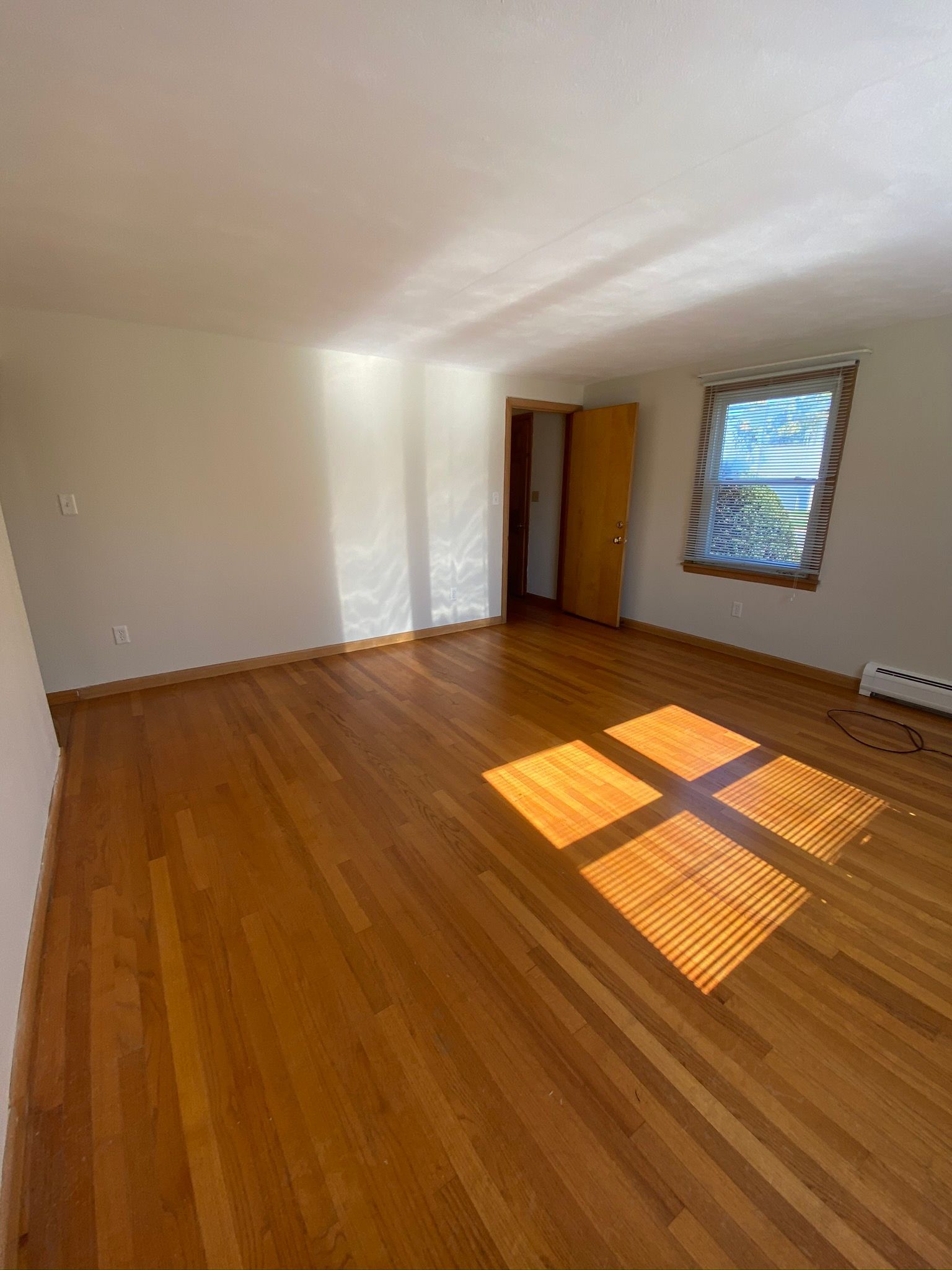 A large empty room with hardwood floors and a window.