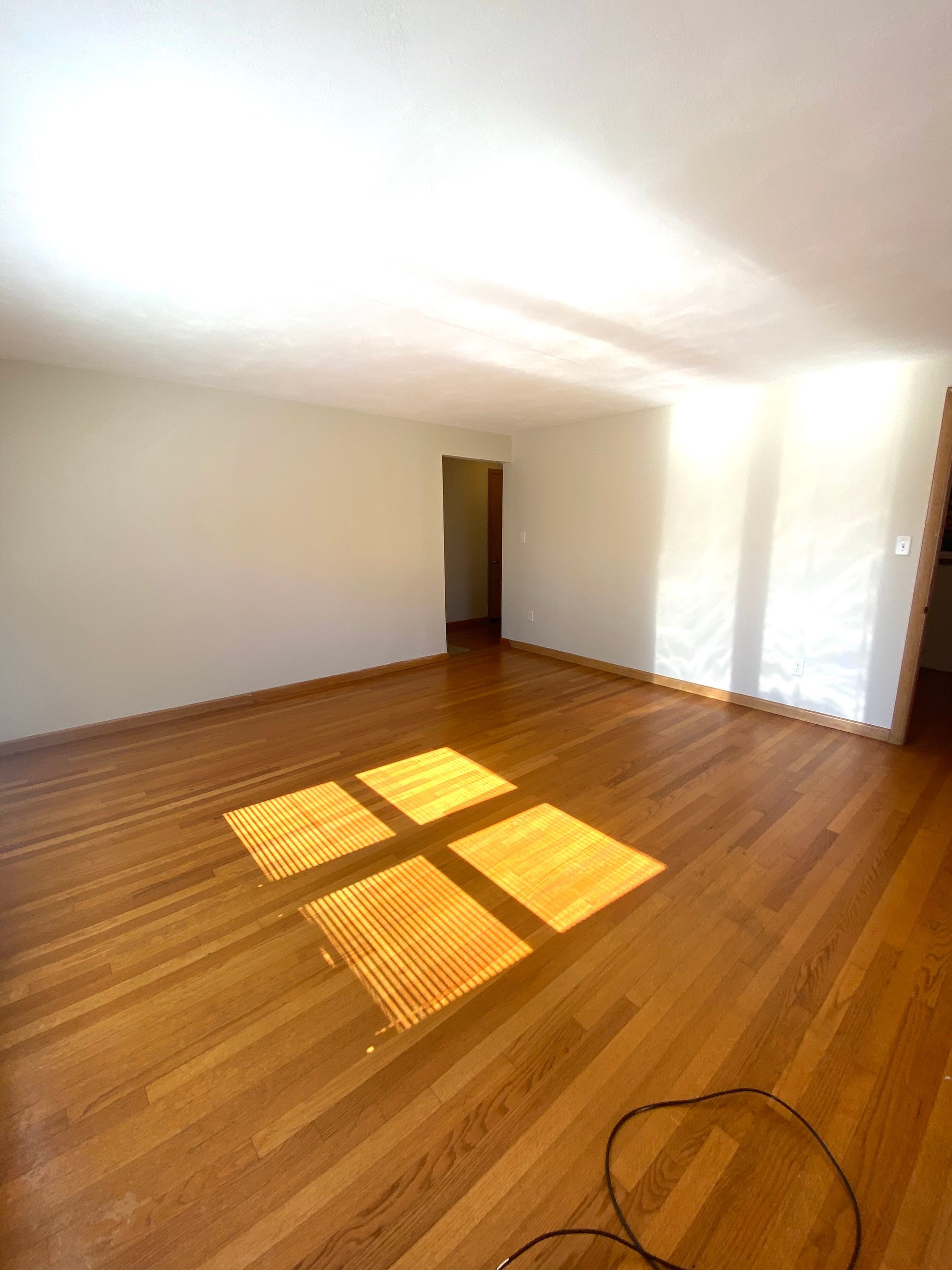 An empty room with hardwood floors and white walls