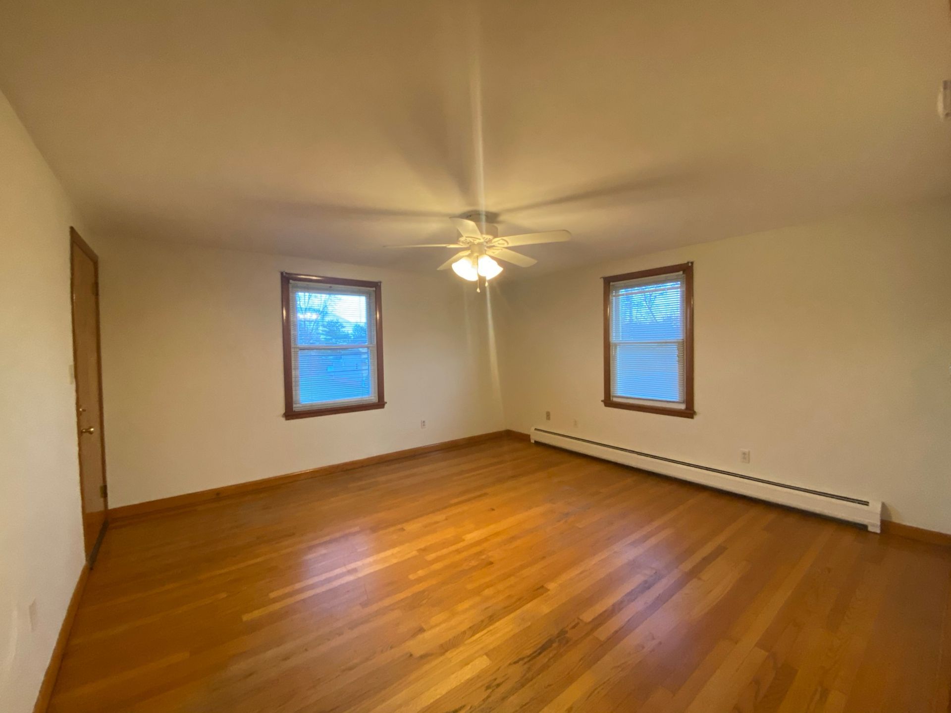 An empty living room with hardwood floors and a ceiling fan.
