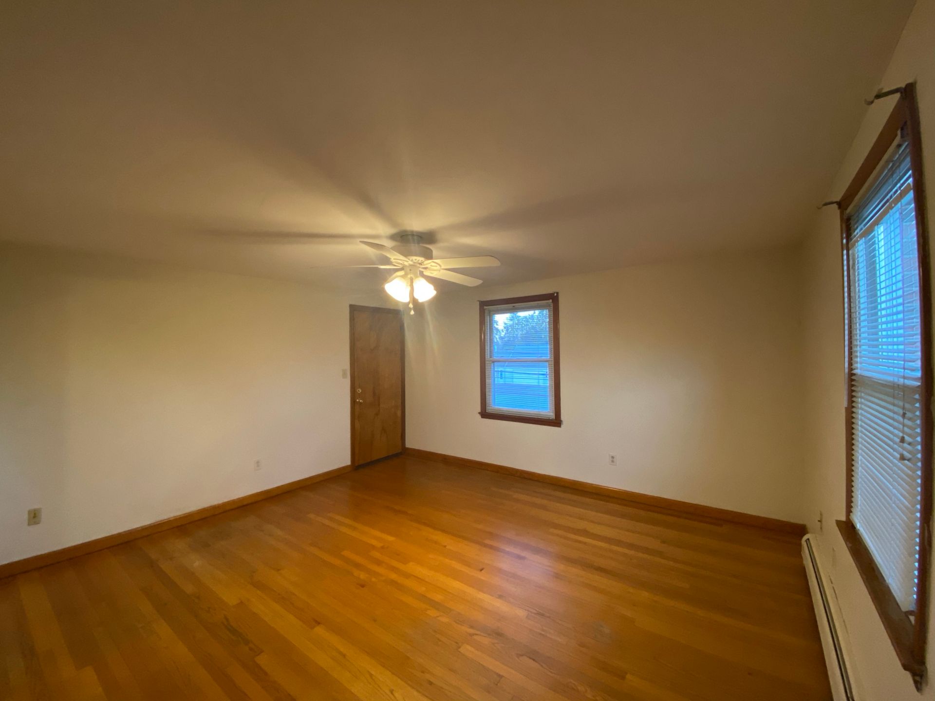 An empty living room with hardwood floors and a ceiling fan.