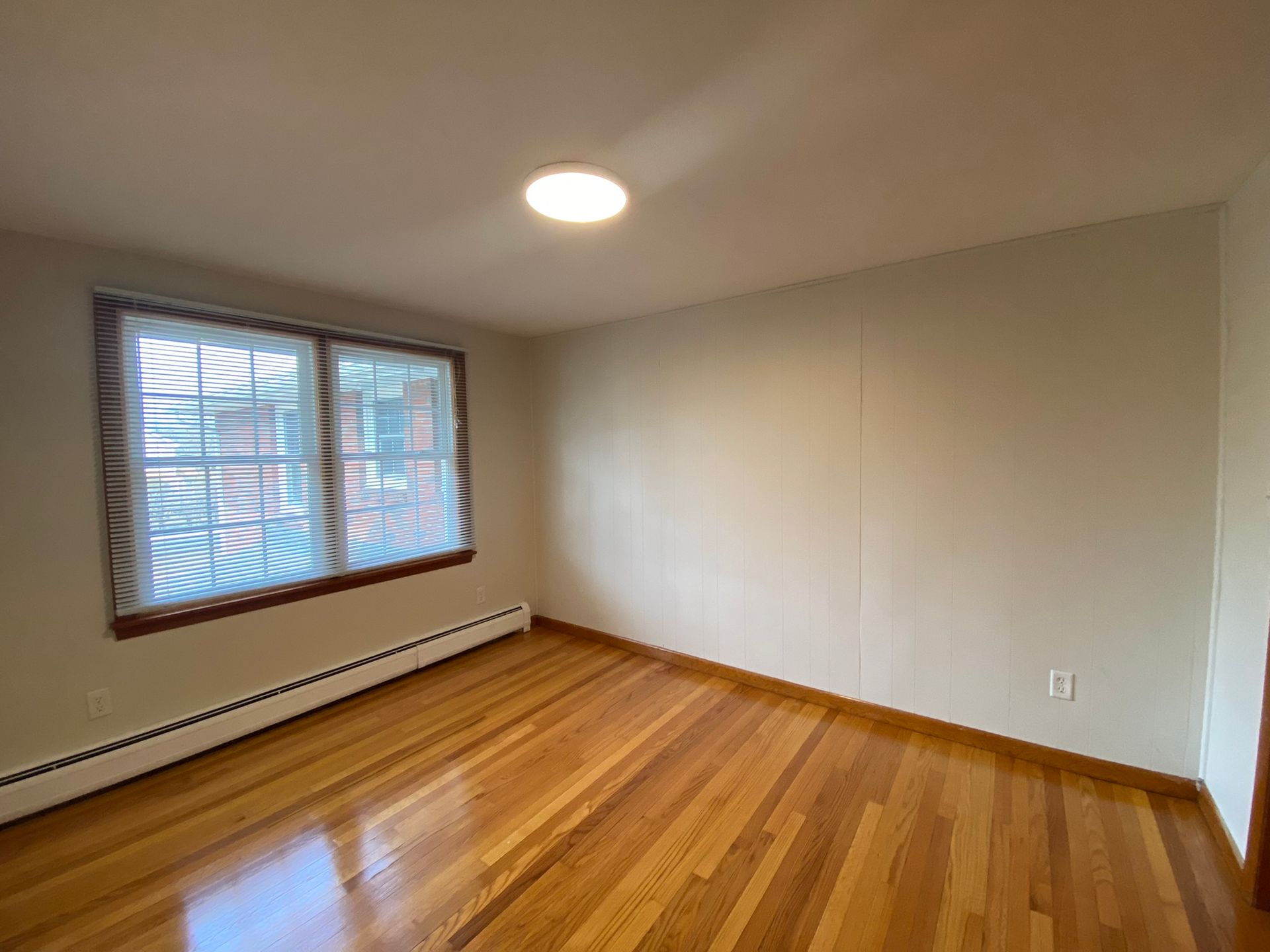 An empty room with hardwood floors and two windows.