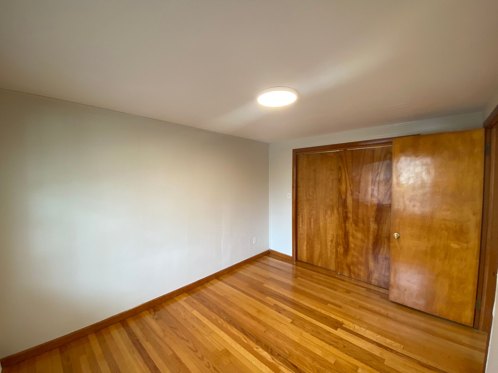 An empty bedroom with hardwood floors and a large closet.