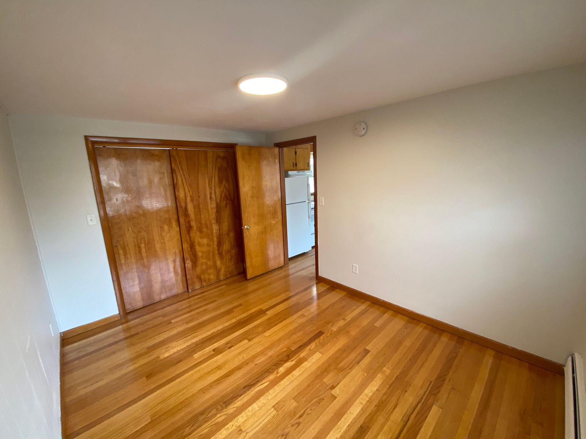 An empty room with hardwood floors and white walls.