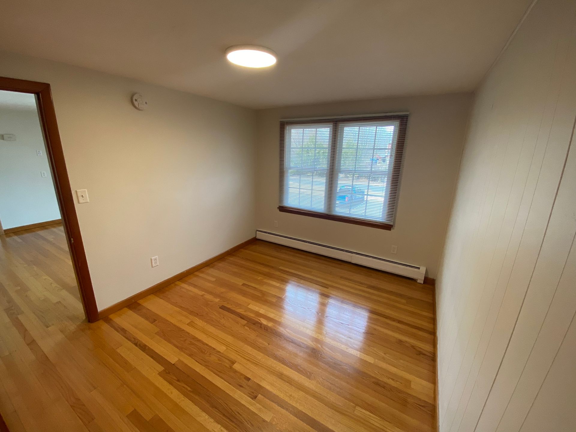 An empty room with hardwood floors and two windows.