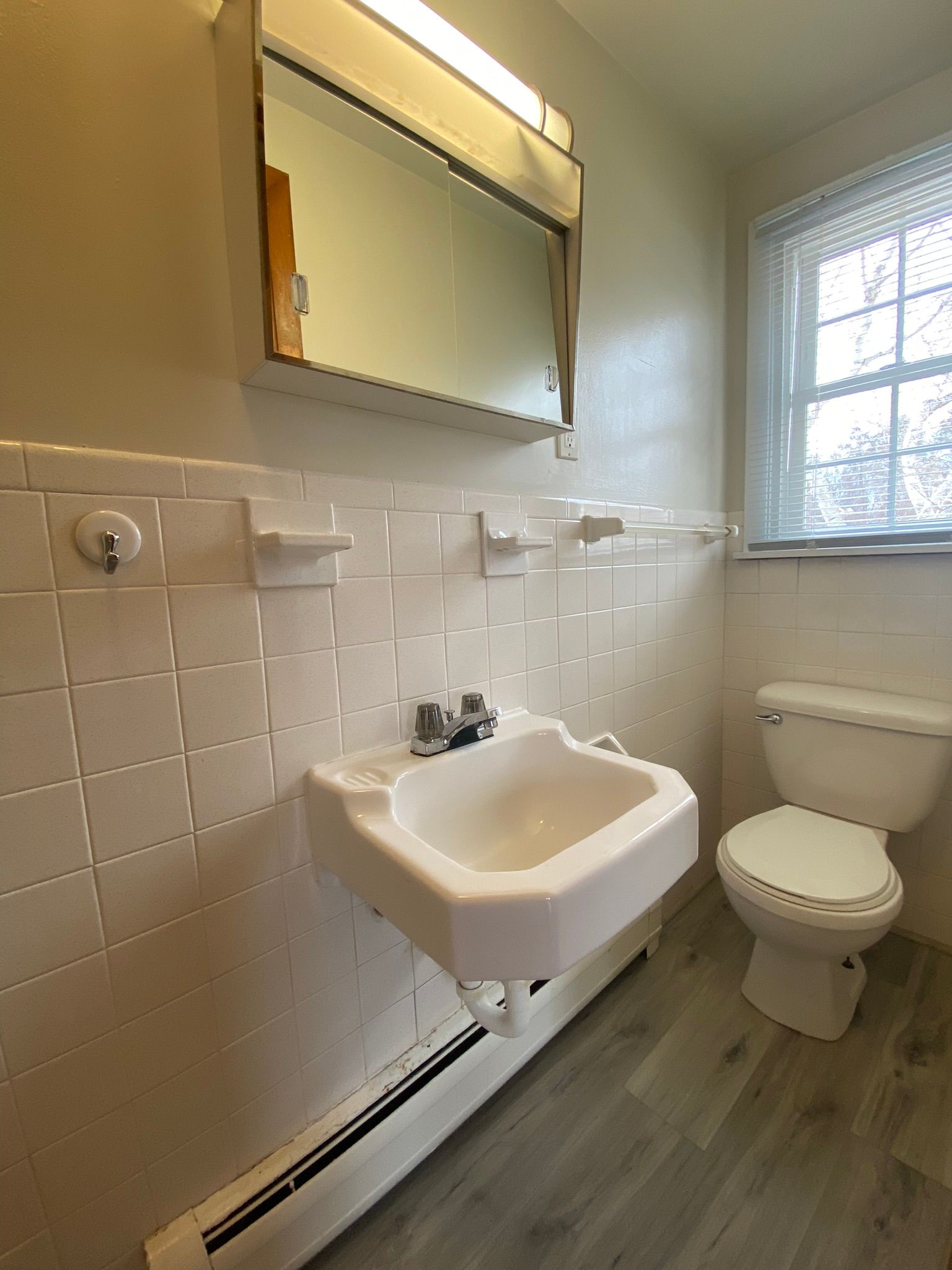 An empty room with hardwood floors and two windows.