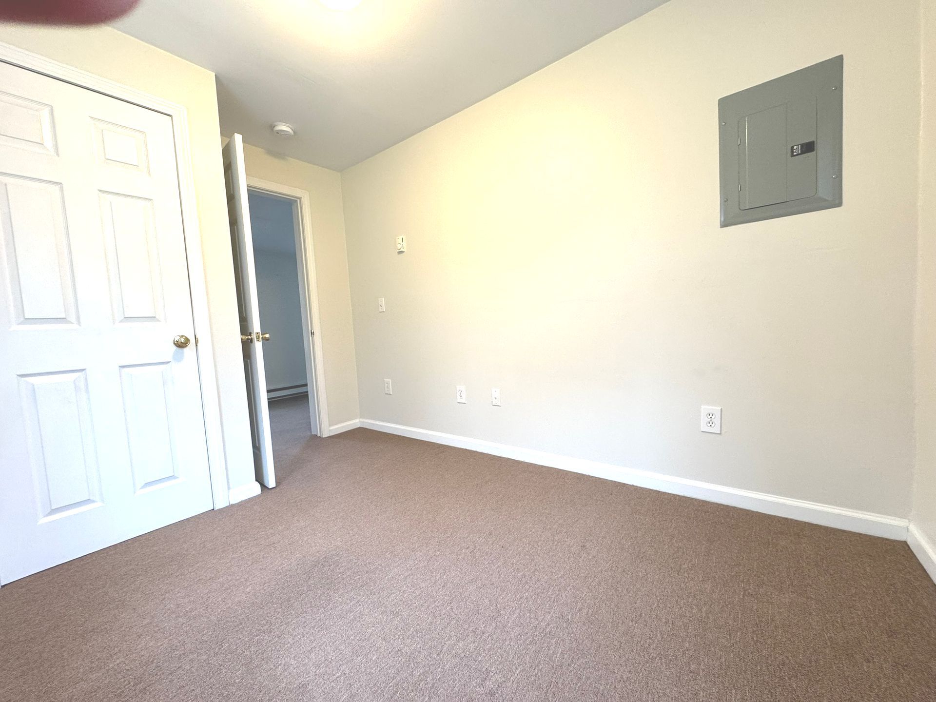 An empty bedroom with a brown carpet and white walls.