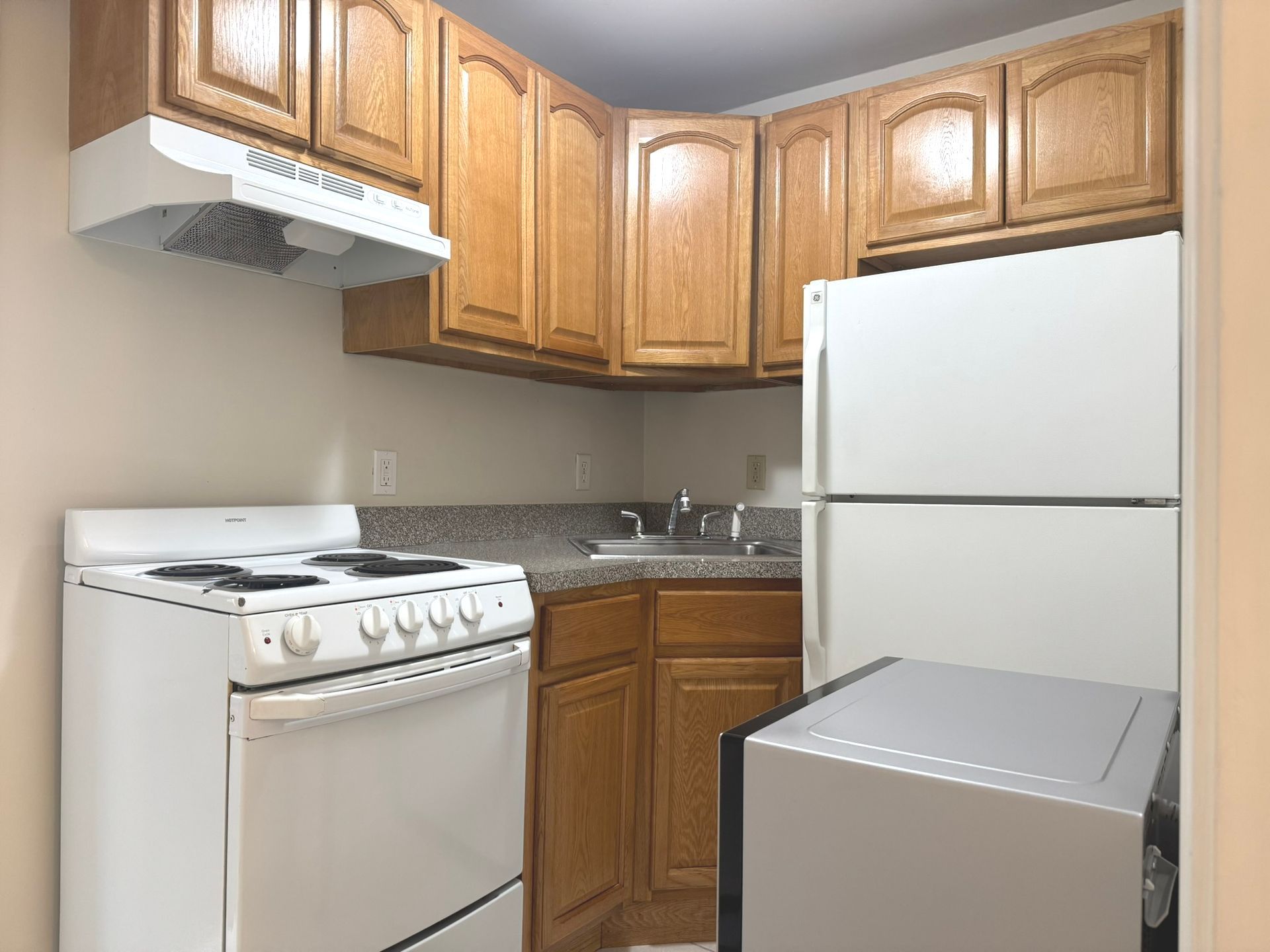 A kitchen with a stove , refrigerator , sink and microwave