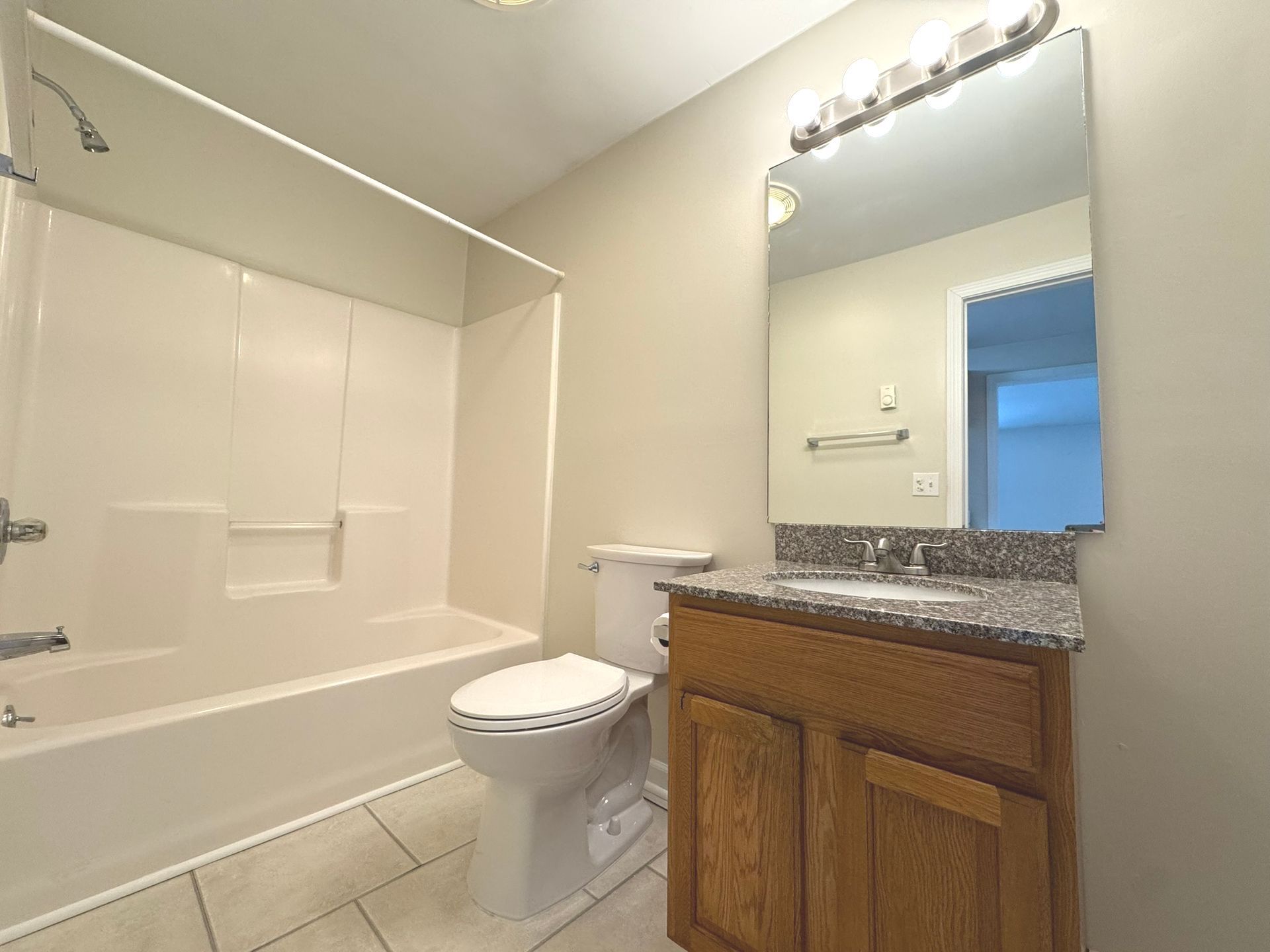 A bathroom with a toilet , sink , bathtub and mirror.