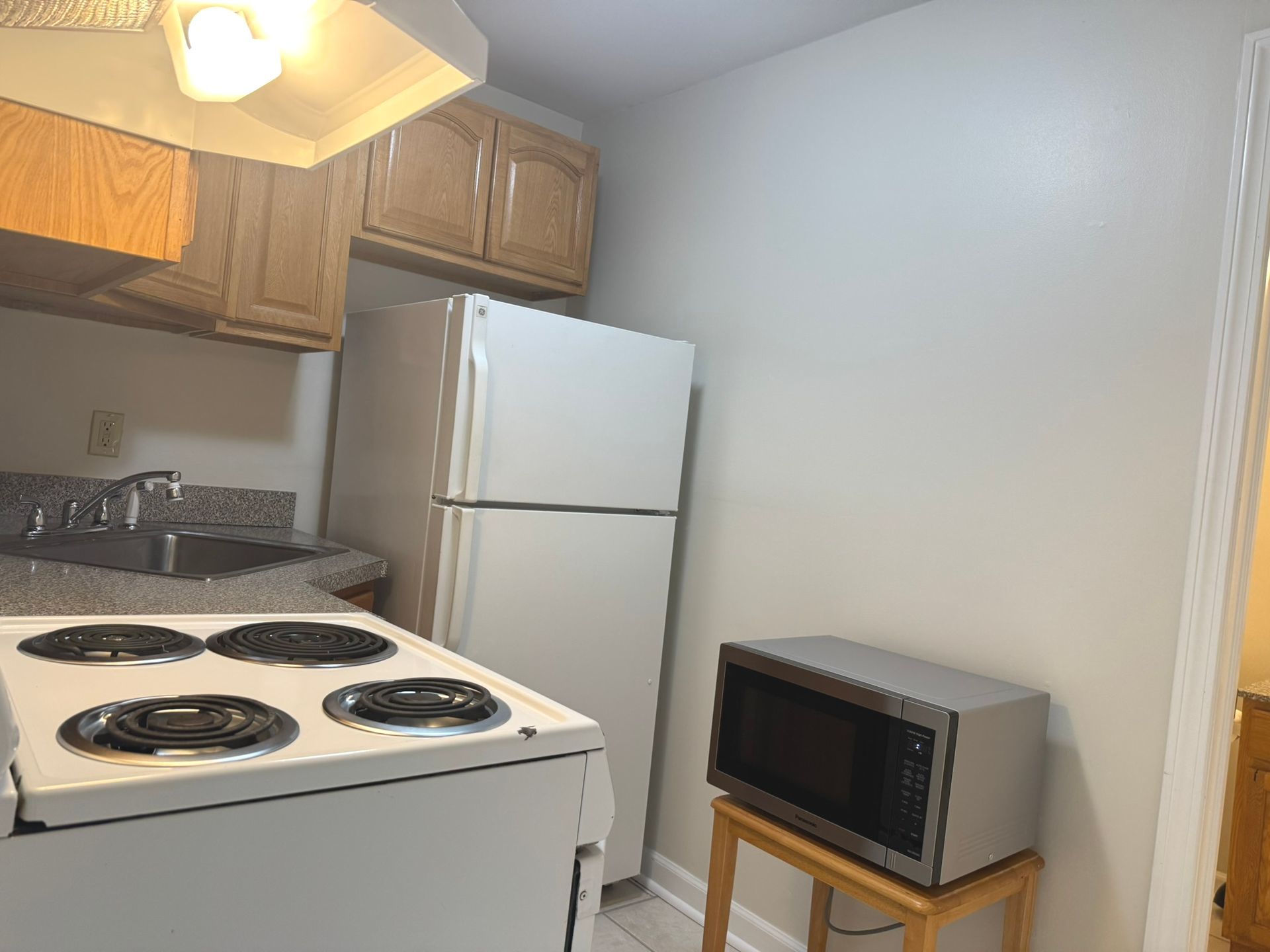 A kitchen with a stove , refrigerator , microwave and sink.