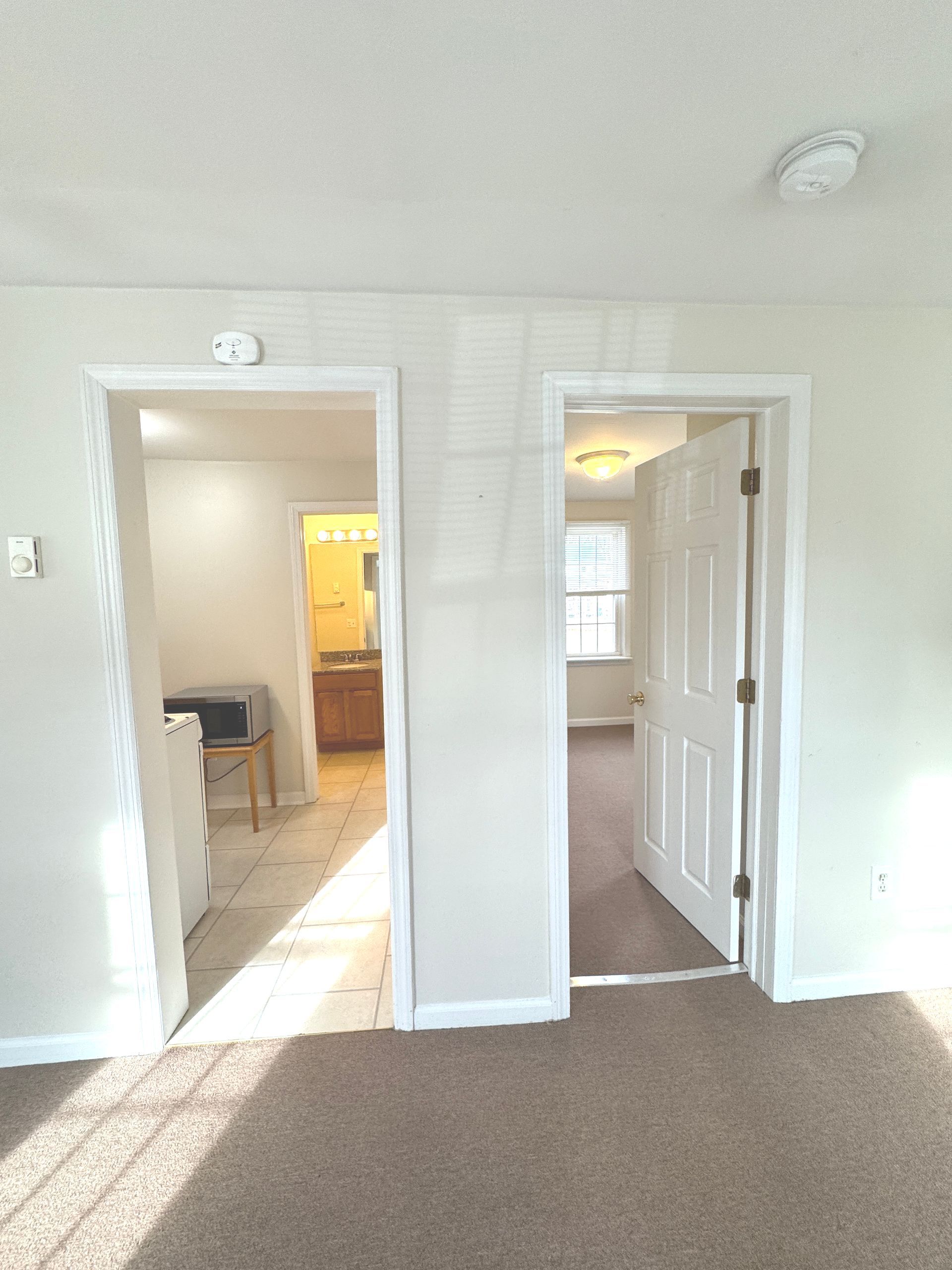 A room with two doors leading to a bathroom and a kitchen.