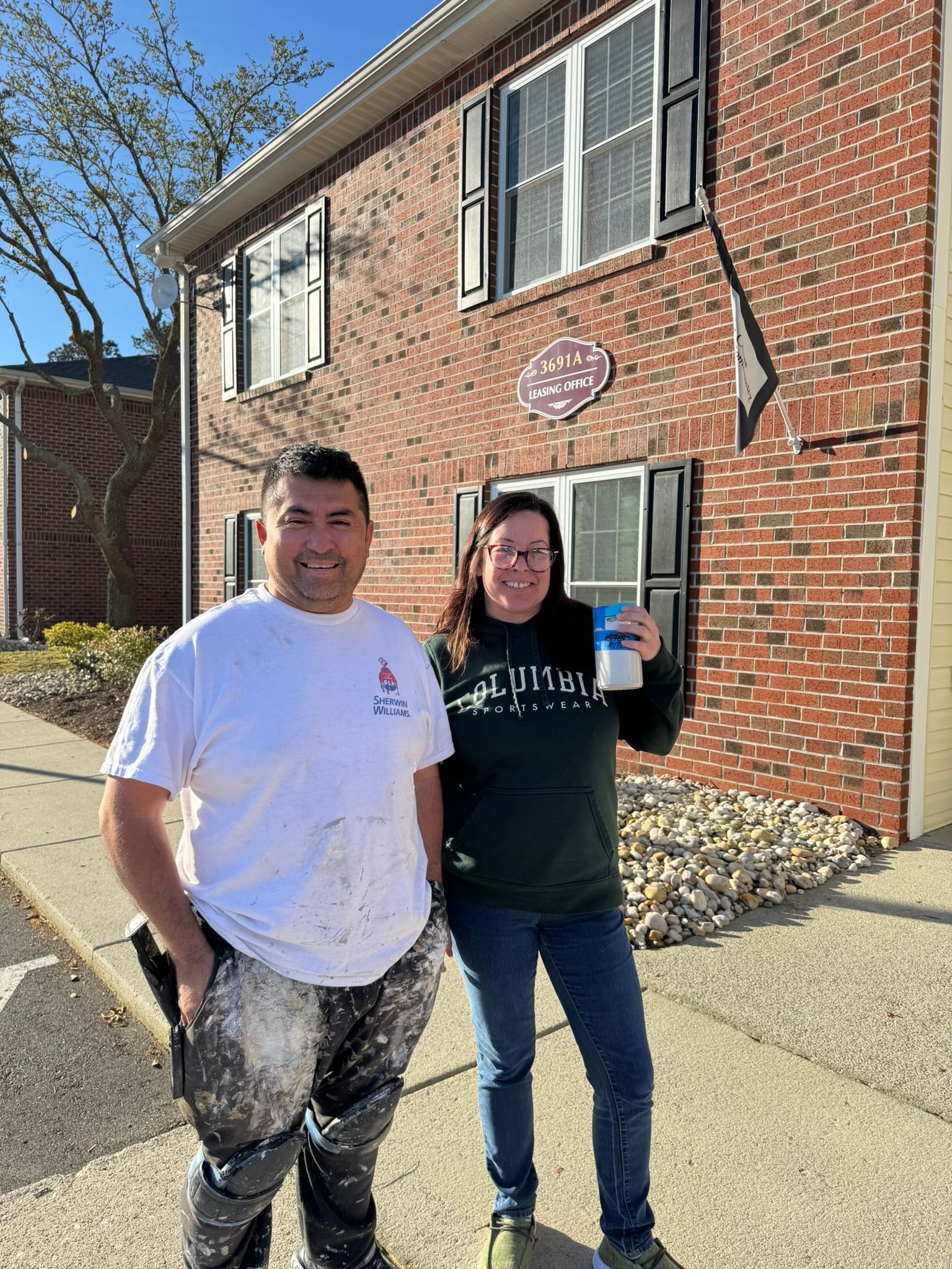A man and a woman are standing in front of a brick building.