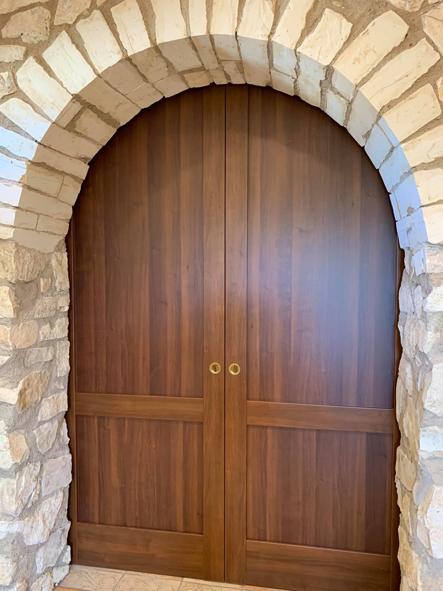 Doppie porte in legno all'interno di un arco in pietra.