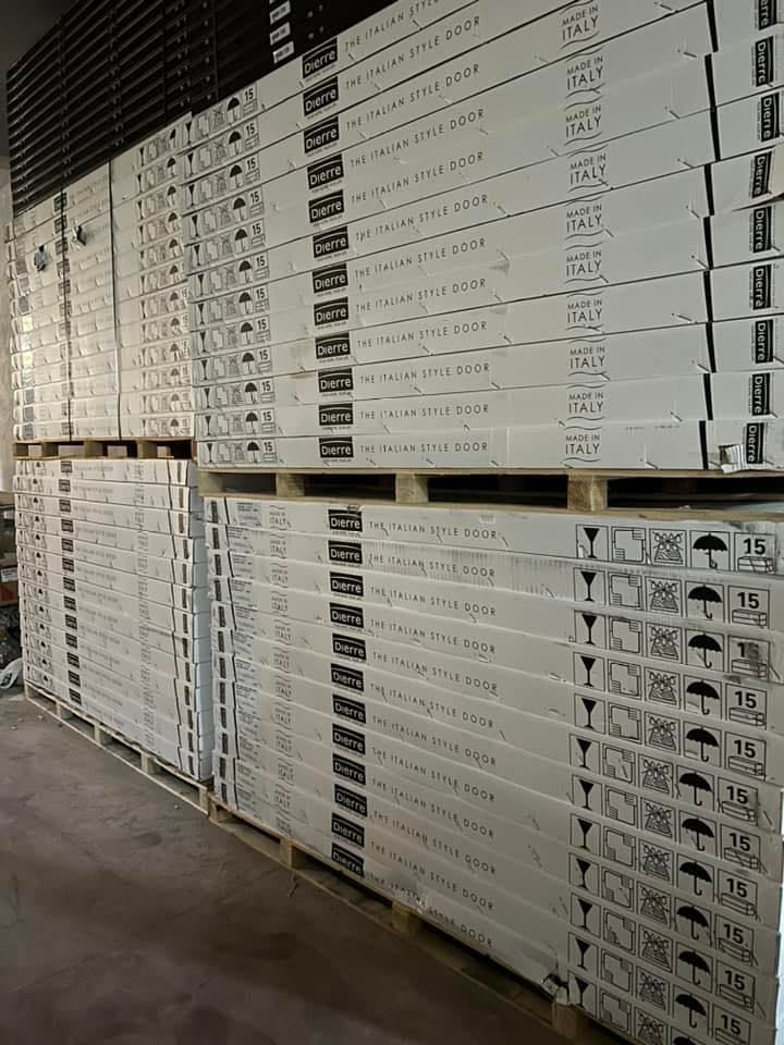 Pallet impilati con scatole rettangolari, probabilmente pavimenti, in un magazzino.