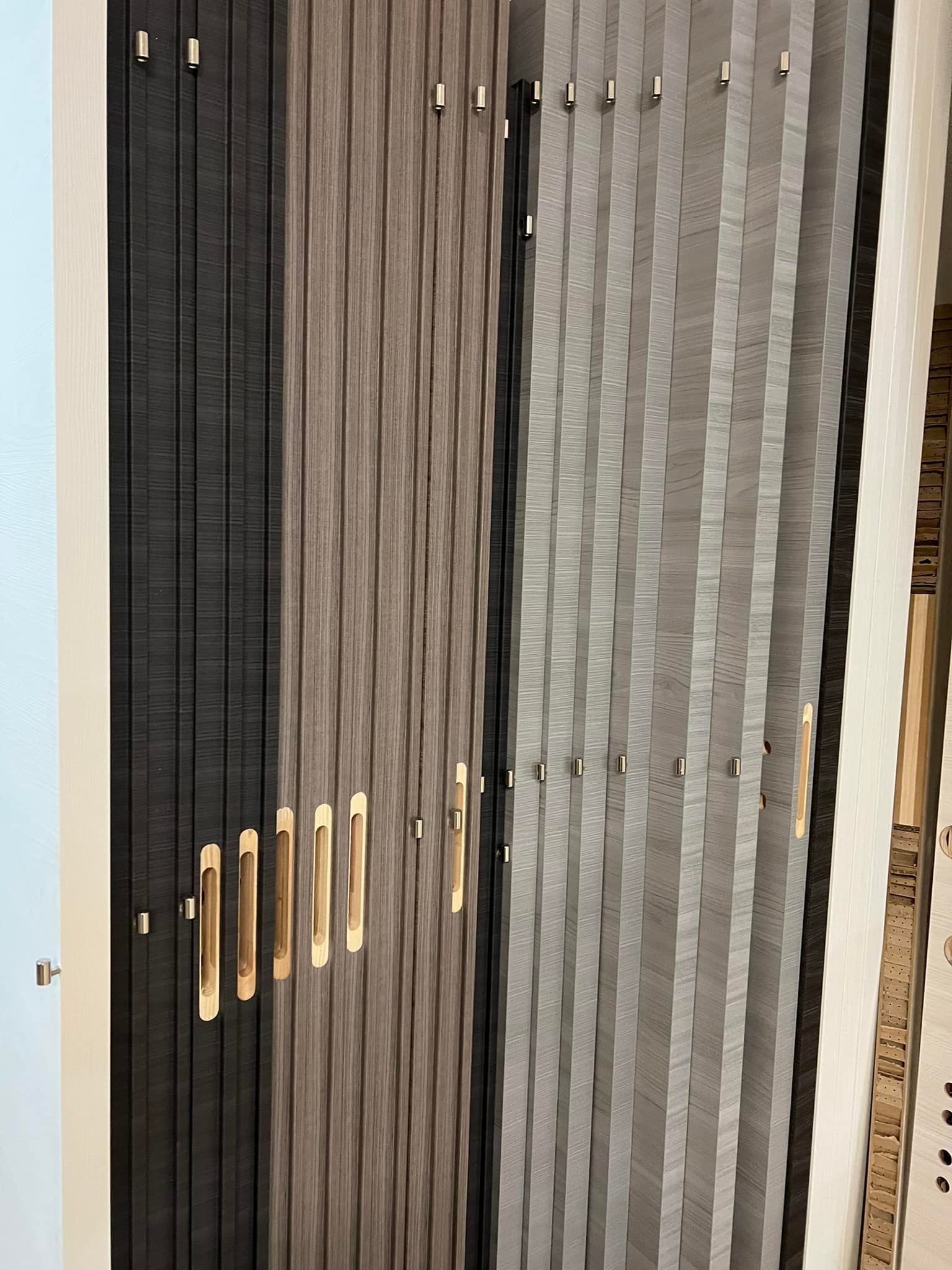 Esposizione di pannelli verticali testurizzati in nero, marrone e grigio, con elementi decorativi dorati.