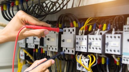 Electricians Hands Testing Current Electric In Control Panel — Servicing Homes & Businesses in Albion Park, NSW