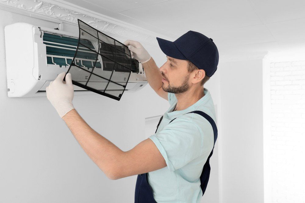 Male Technician Cleaning Air Conditioner Indoors — Servicing Homes & Businesses in Wollongong