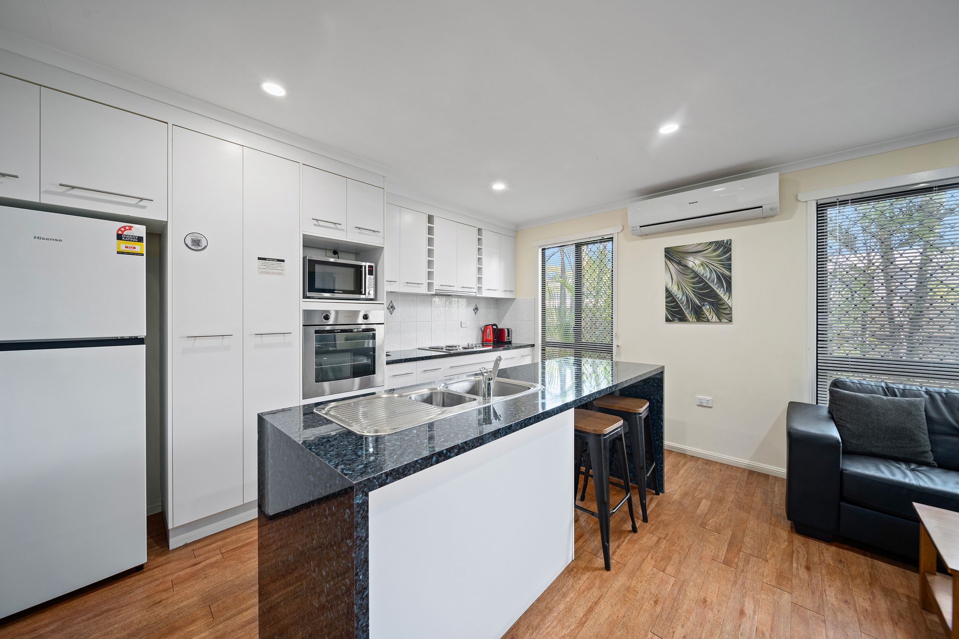 A kitchen with white cabinets , a refrigerator , a microwave , and a sink.