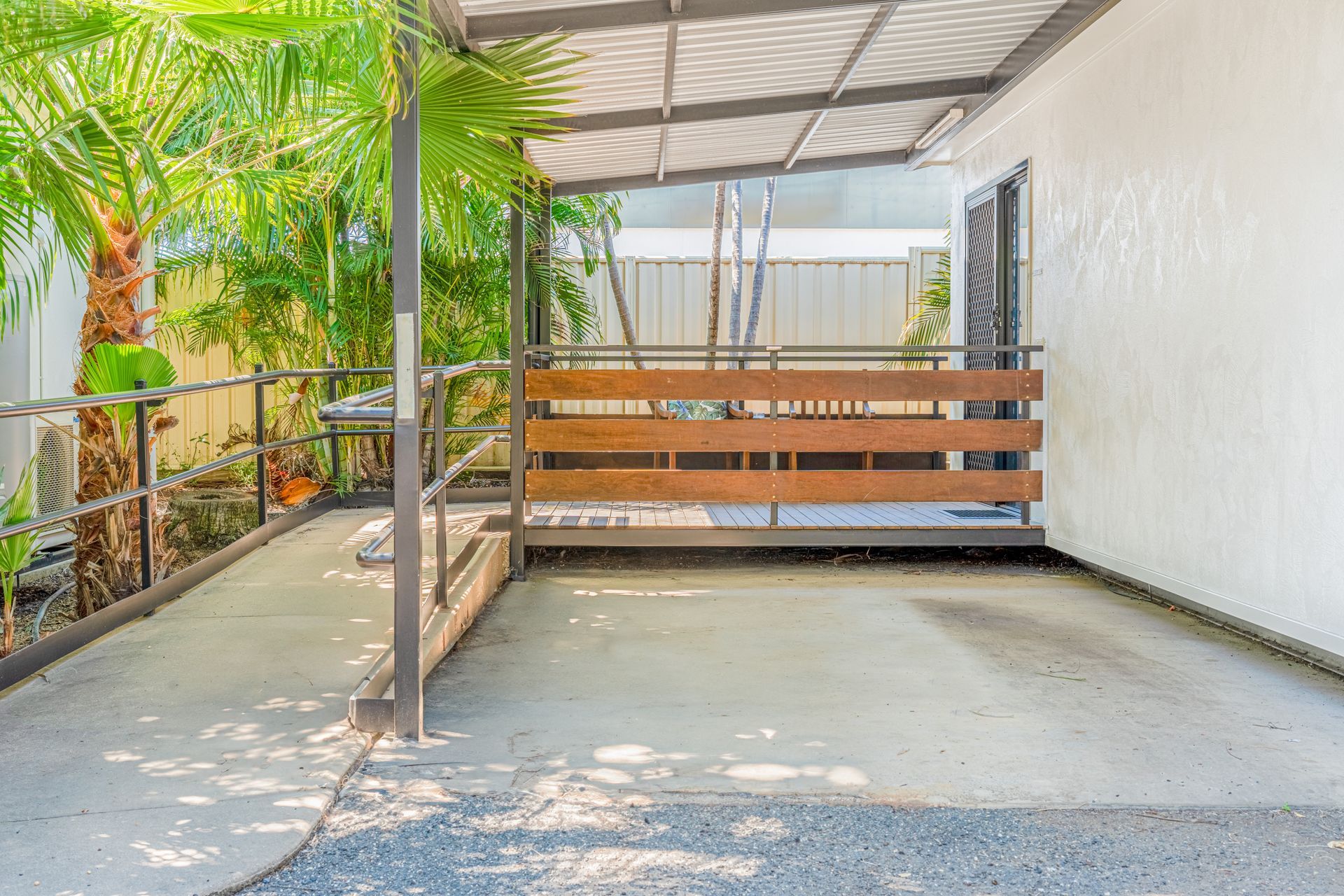 A carport with a wooden railing and a ramp leading to it.