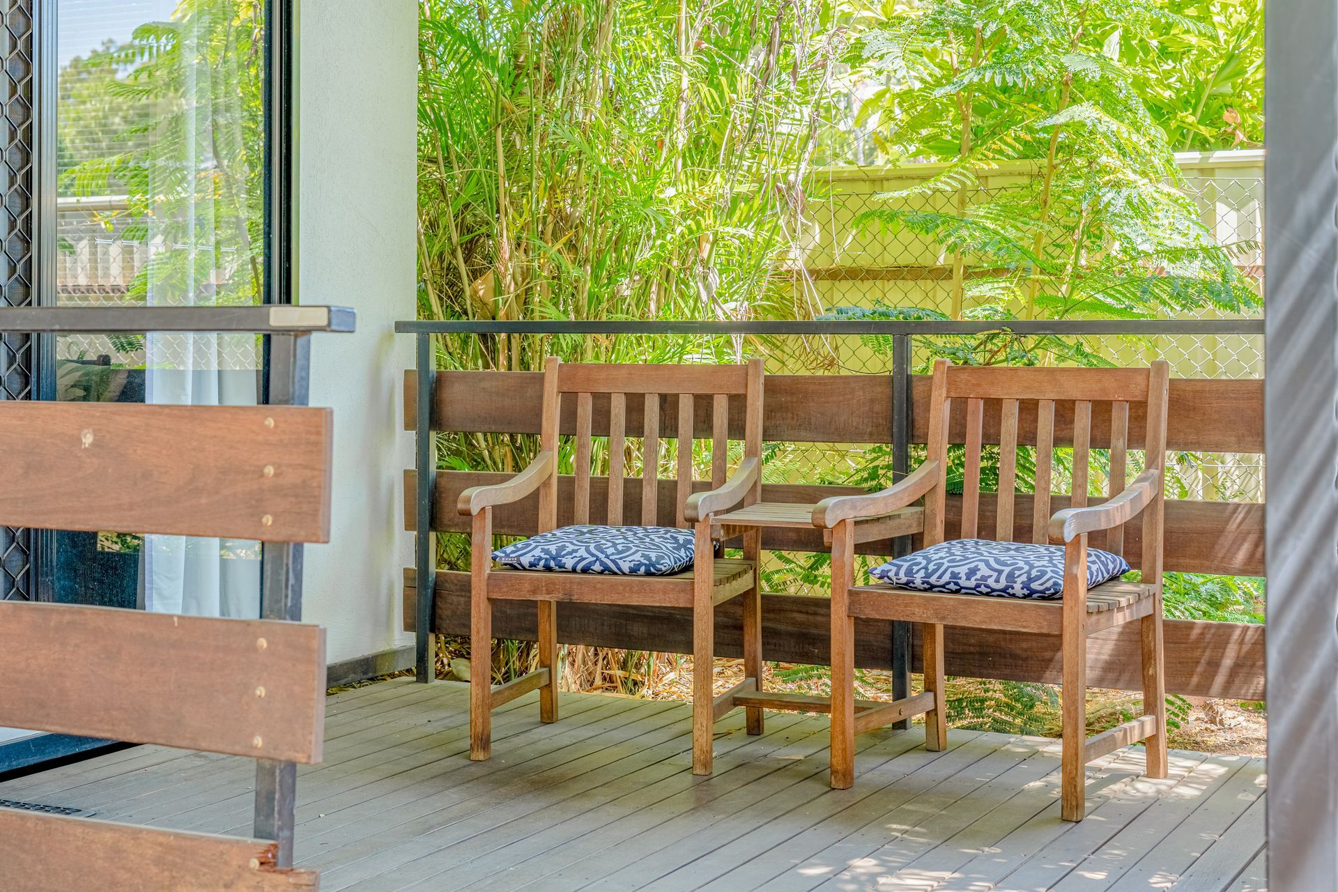 Two wooden chairs are sitting on a wooden deck.
