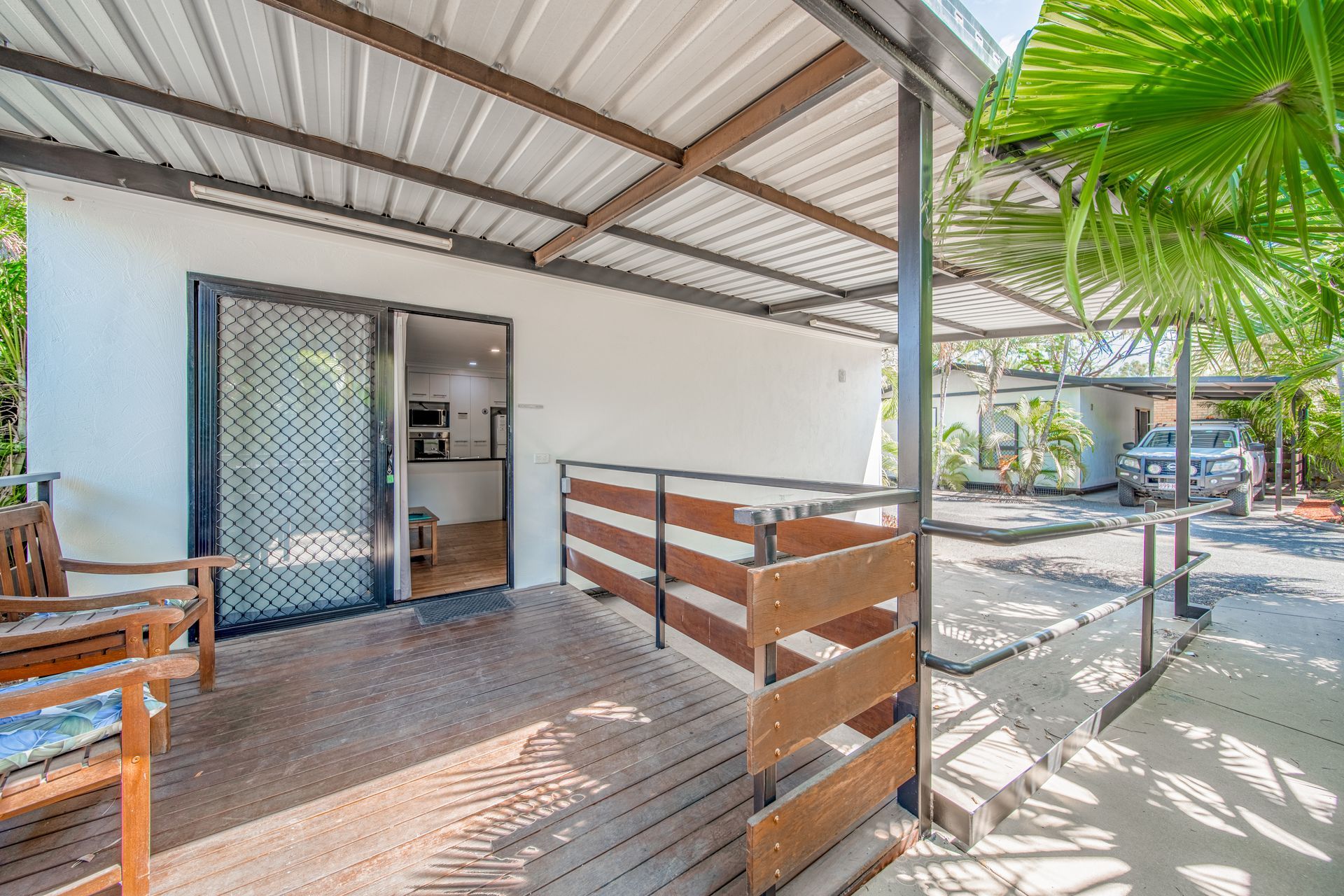 A white house with a wooden deck and a metal roof.