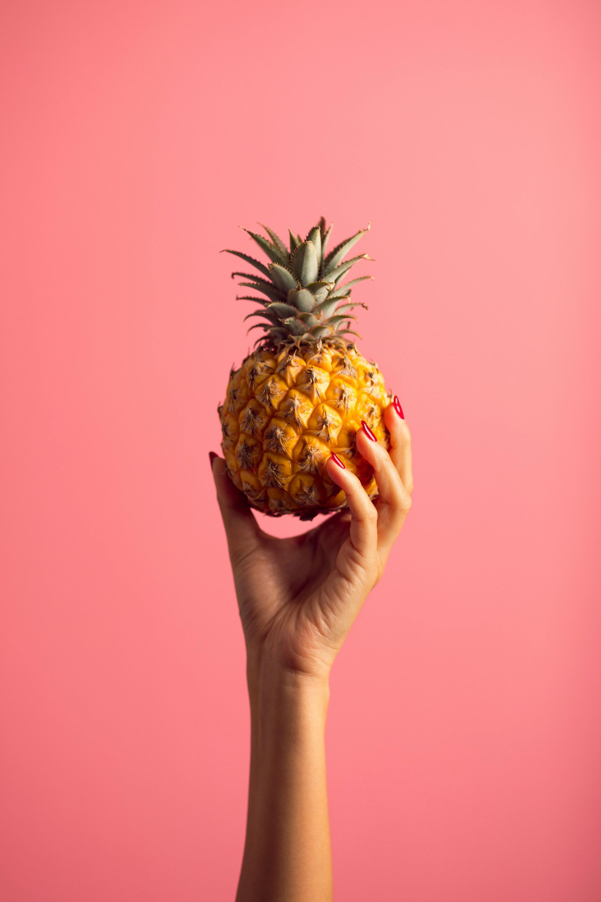 woman holding pineapple with pink background | Springfield mo