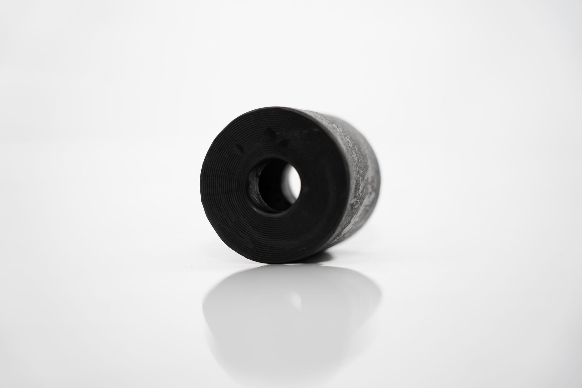 Un anillo de goma negro con un agujero en el medio sobre una superficie blanca.