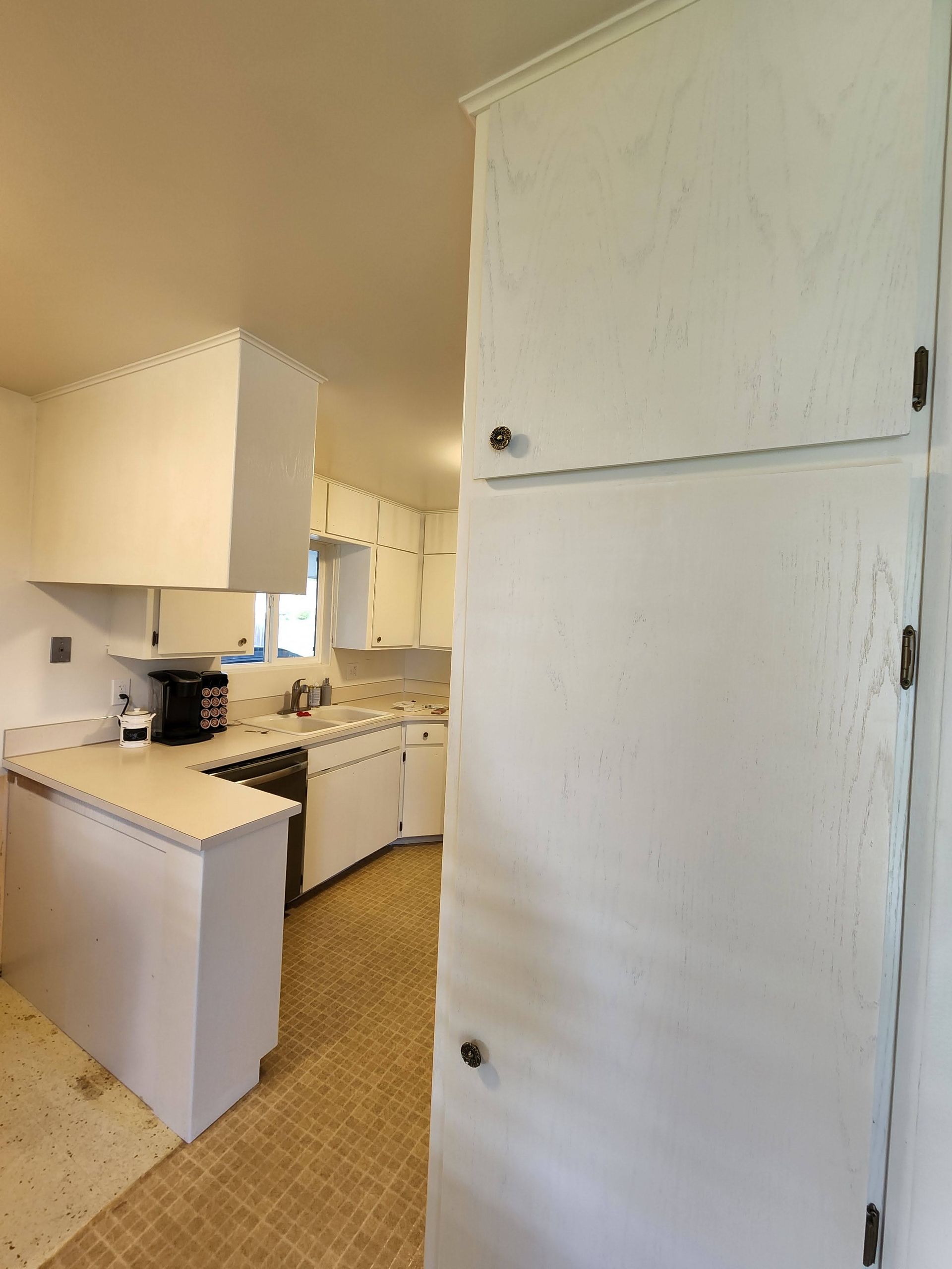 White kitchen with cabinets, countertops, and appliances. Pale yellow floor.