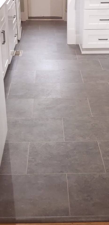 Gray tiled floor in a kitchen with white cabinets.