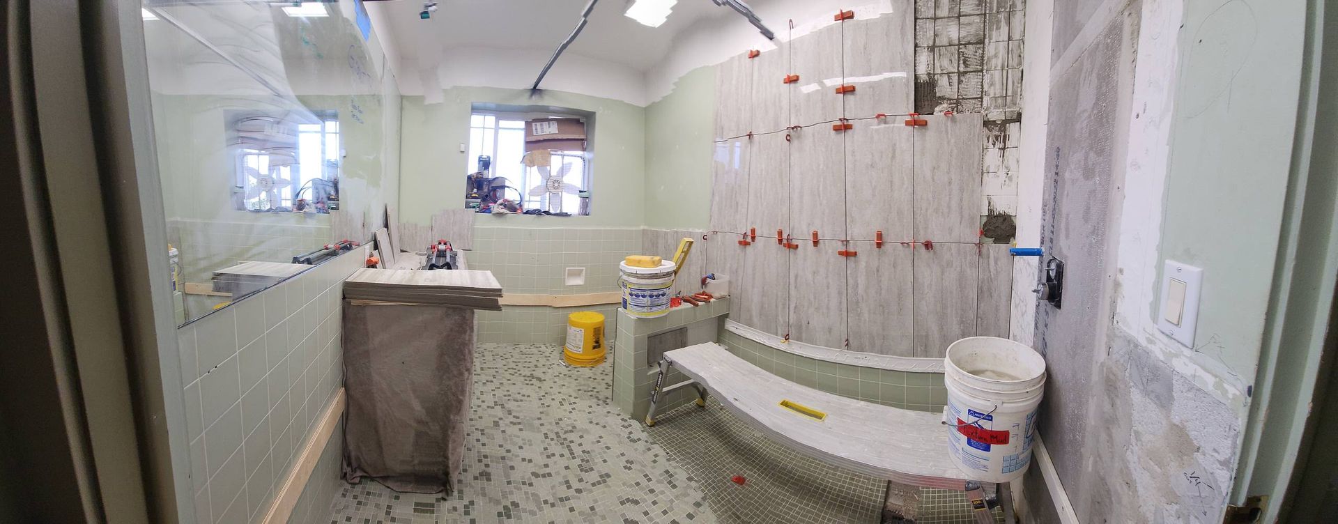Bathroom under construction with tile and a curved bench.