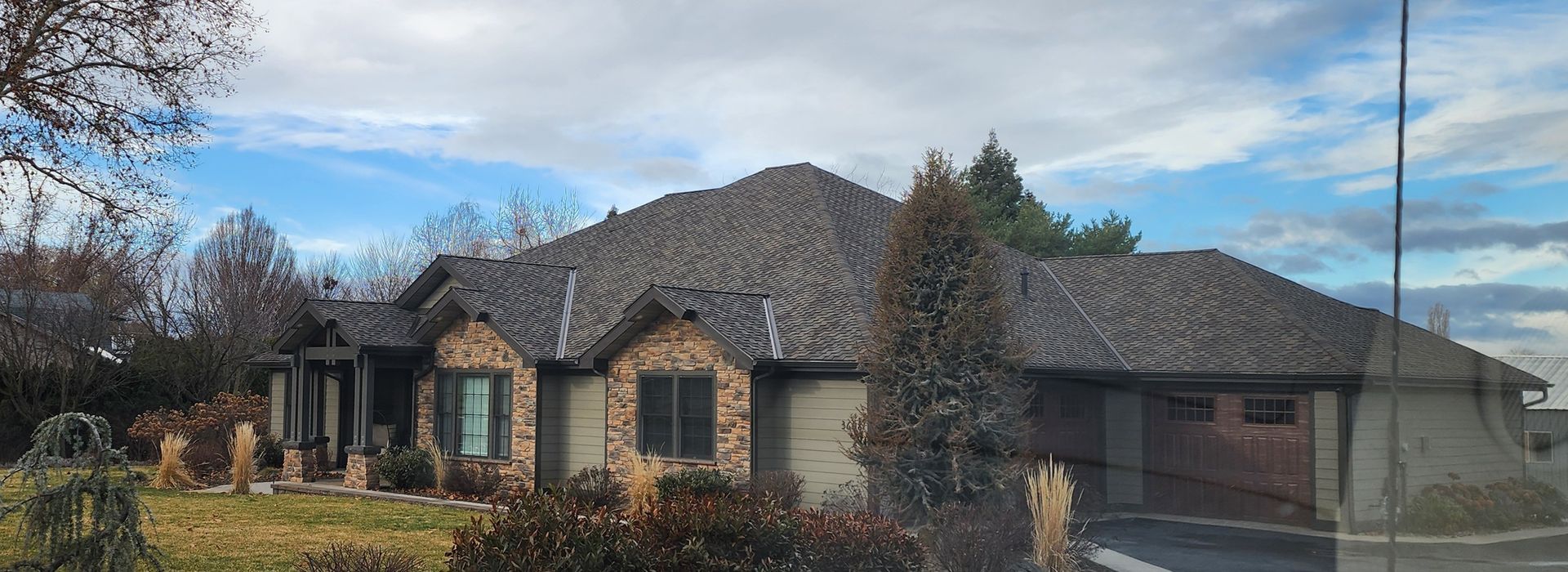 Open carport with white siding, wooden beams, and a gravel driveway.
