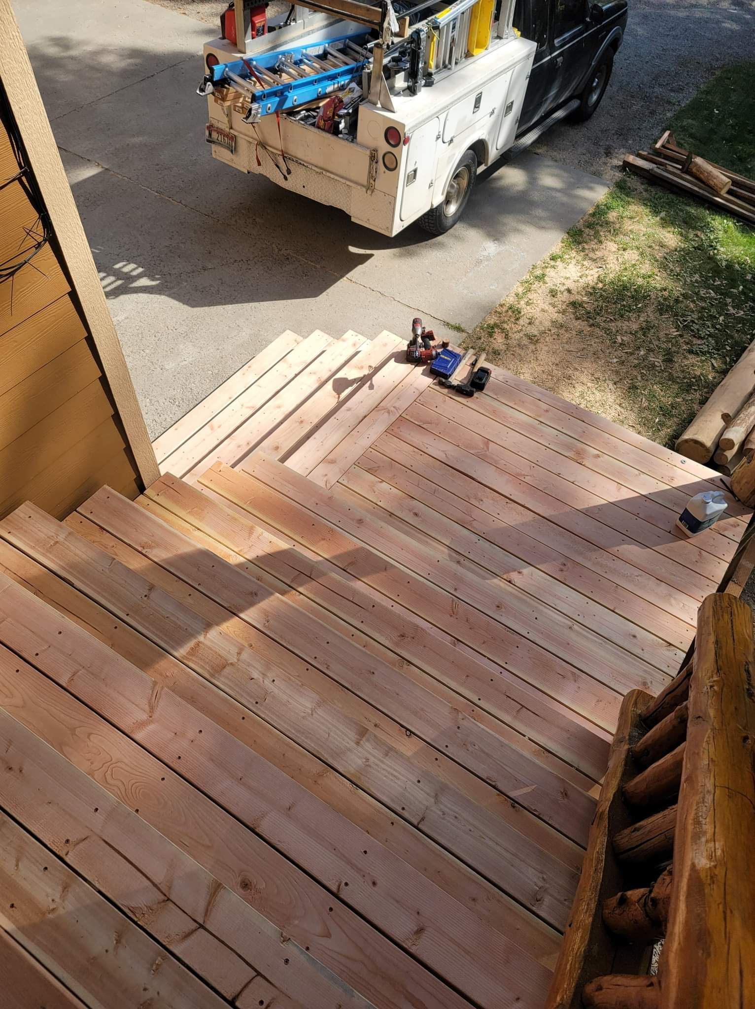 Wooden outdoor staircase leads down to a driveway. A truck is parked on the driveway.