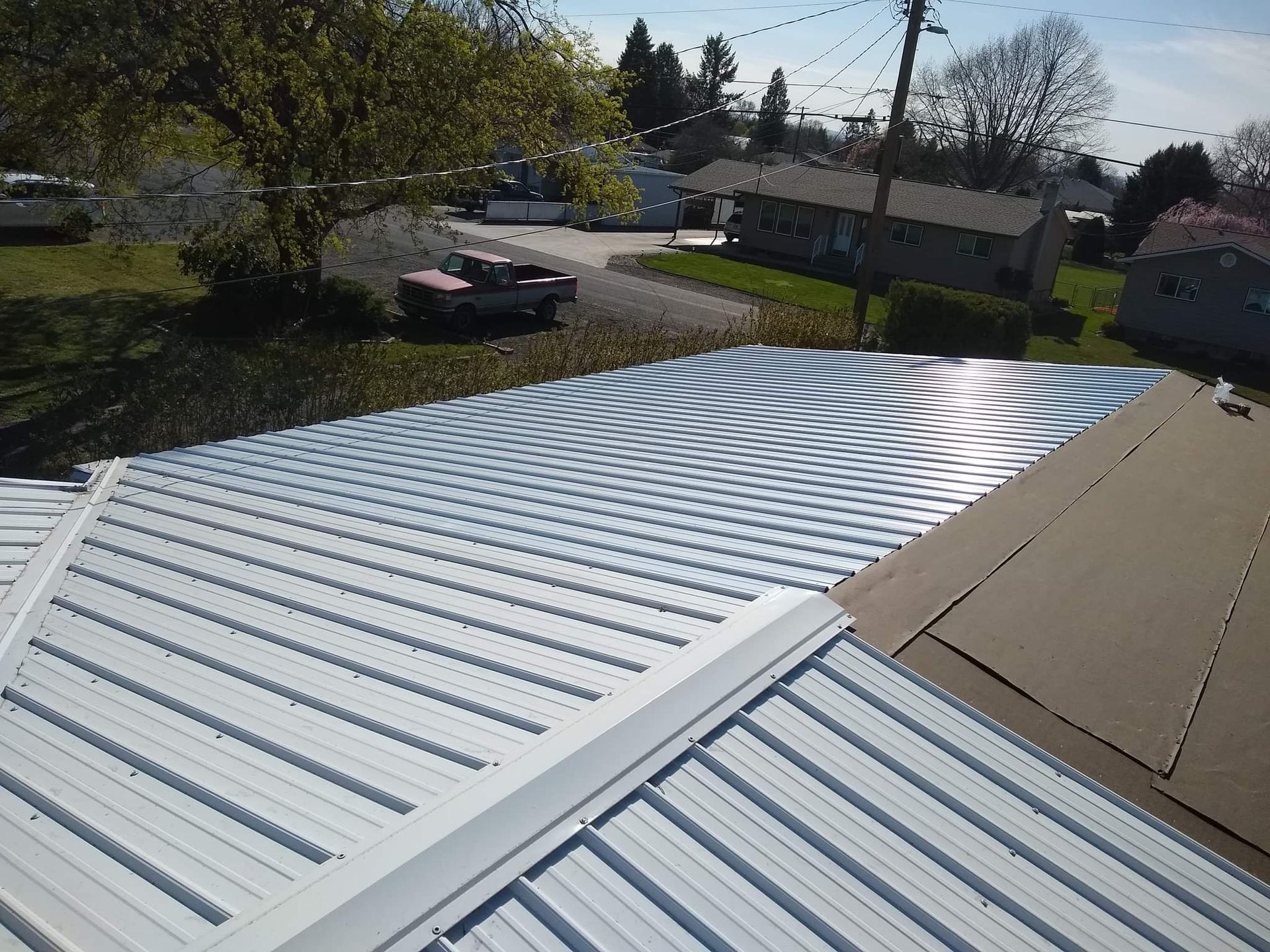 Tan house with black car in driveway, blue sky background.