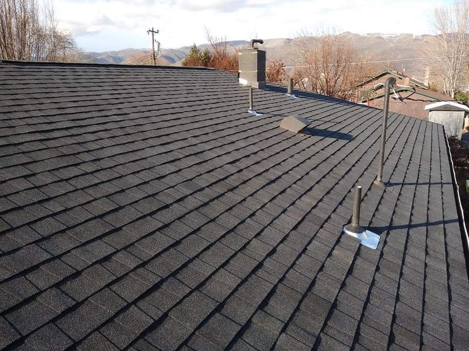 Beige two-story house with attached garage; vehicles parked in driveway; blue sky.