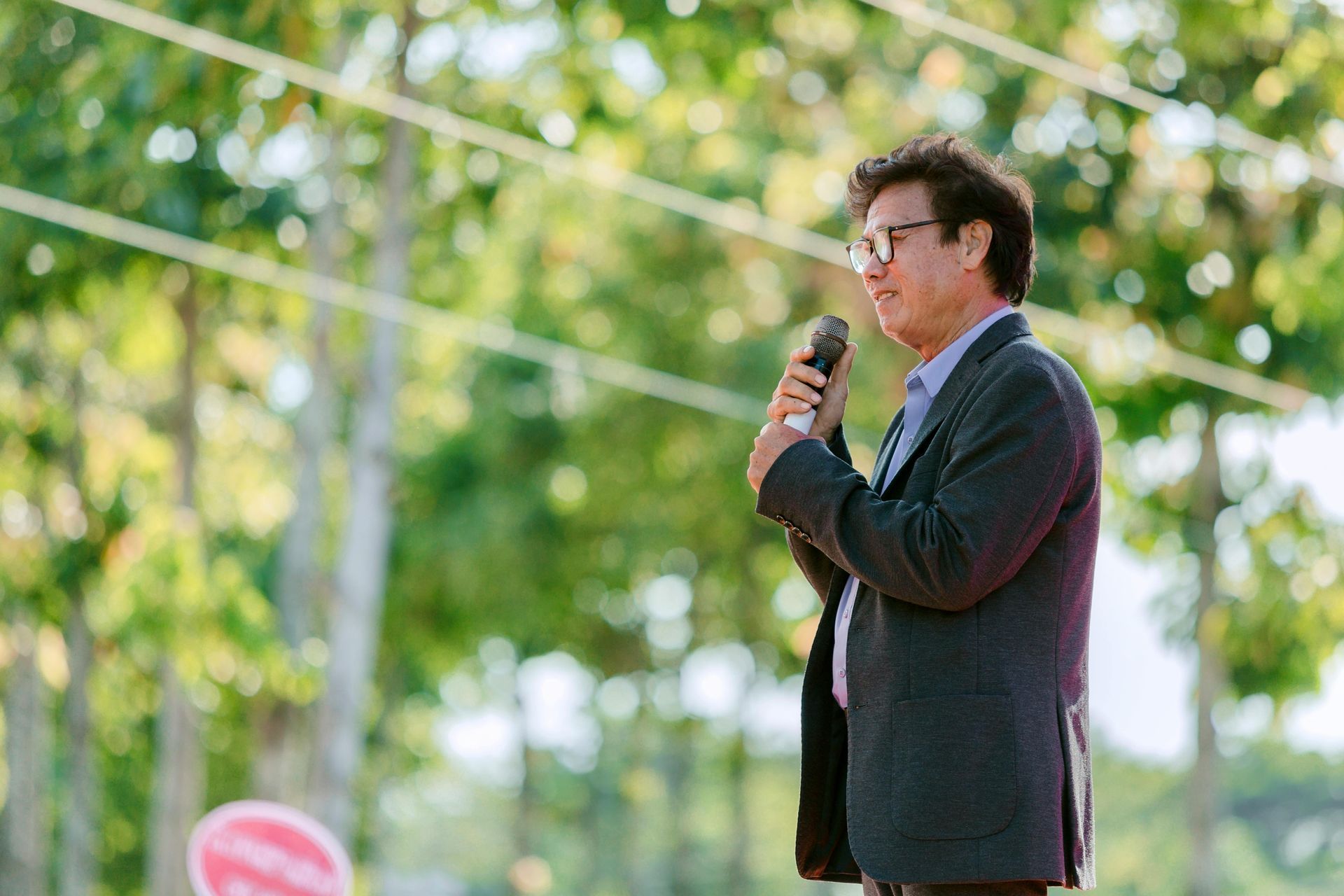Woman in red dress speaking at a podium, American flag in background, gesturing with her hands.